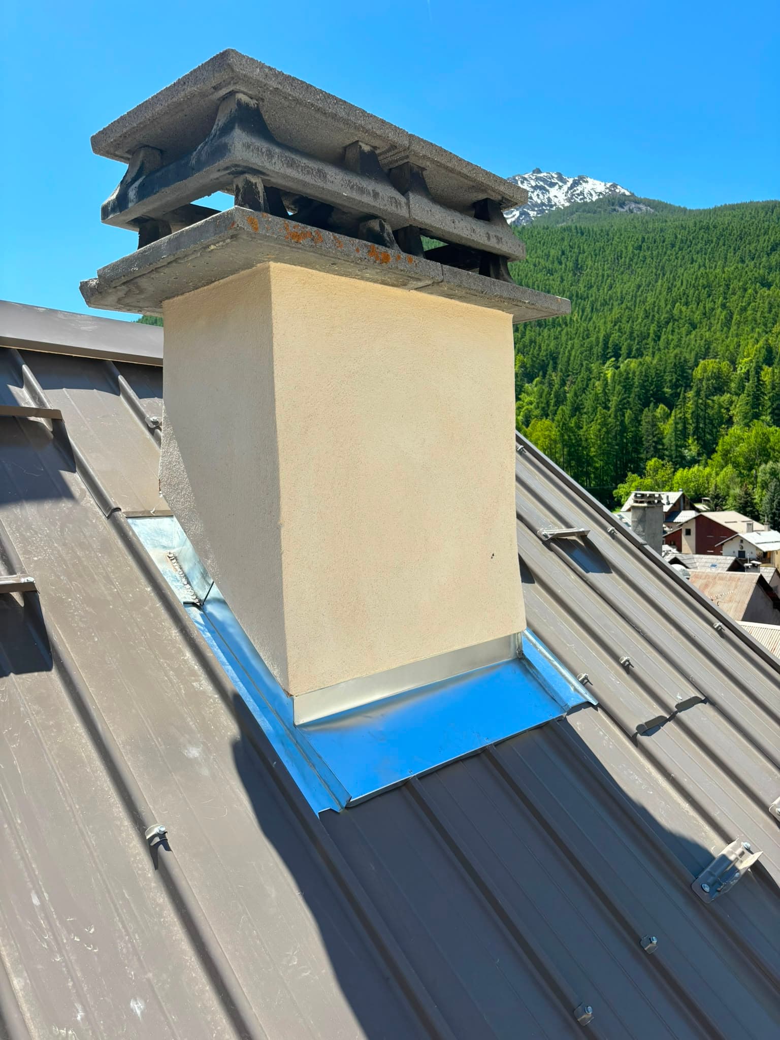 Souche de cheminée neuve sur une toiture en zinguerie, vue montagne