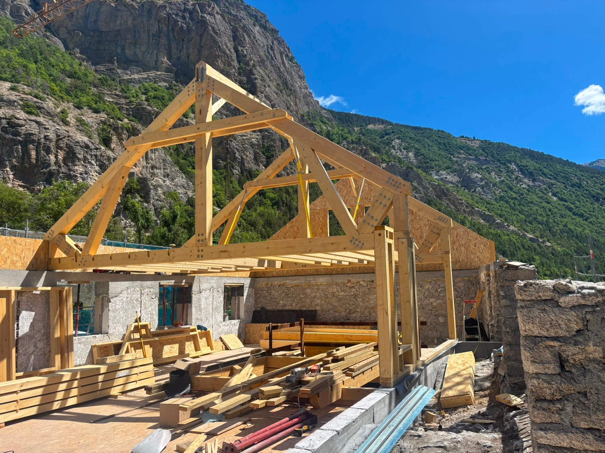 Charpente en ossature bois neuve en cours de montage sur une dalle
